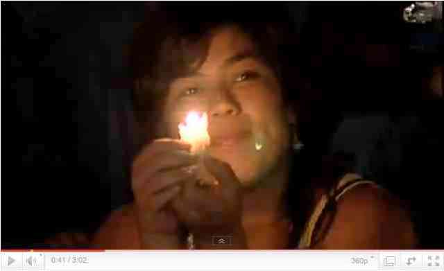 Woman with candle during Earth Hour, image from Earth Hour 2011 Official Video/earthhour.org, youtube.com